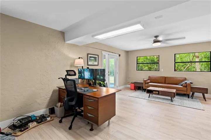 Office featuring a textured wall, light wood-type flooring, and ceiling fan