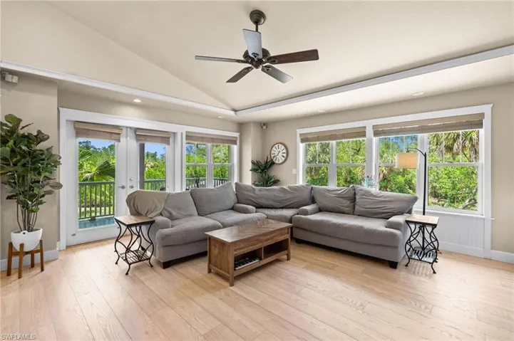 Living area with lofted ceiling, light wood finished floors, a ceiling fan, recessed lighting, and plenty of natural light