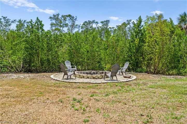 View of grassy yard with a patio and an outdoor fire pit