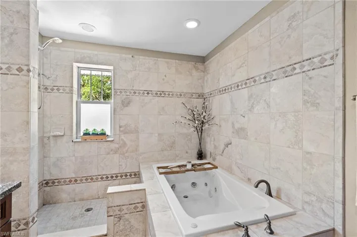 Bathroom with a tub with jets, a walk in shower, recessed lighting, and vanity