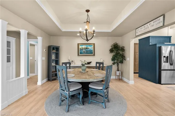 Dining area featuring a tray ceiling, light wood-type flooring, and a chandelier