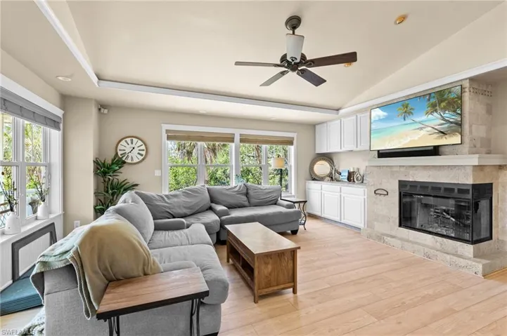 Living area featuring light wood finished floors, radiator, a glass covered fireplace, and a ceiling fan