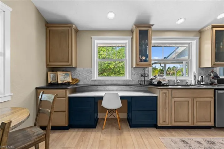 Kitchen with glass insert cabinets, light wood-type flooring, tasteful backsplash, and recessed lighting
