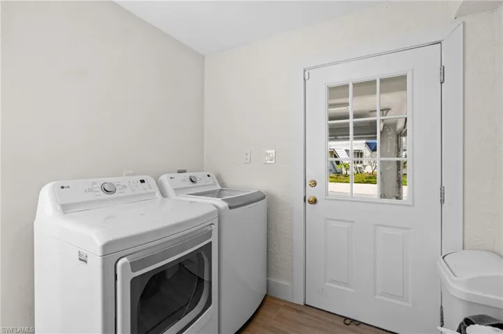 Laundry room with wood finished floors, a textured wall, and washing machine and dryer