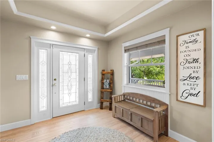 Foyer entrance featuring light wood-style floors, recessed lighting, and a tray ceiling