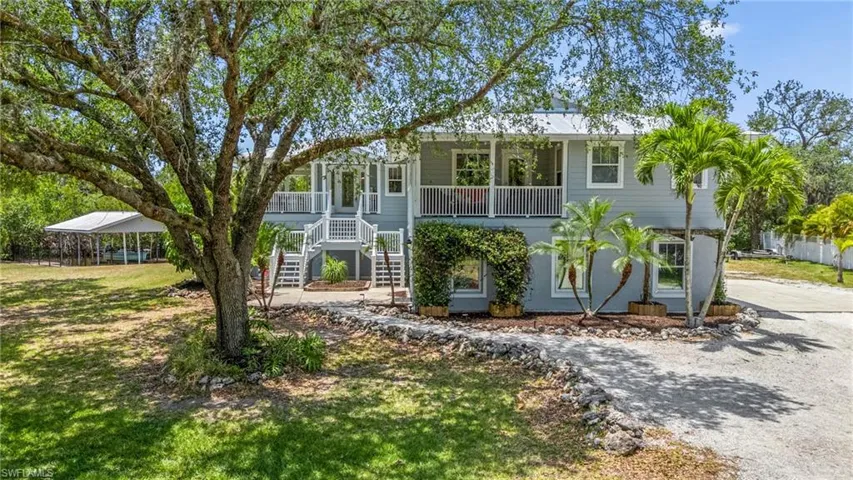 Beach home with a porch, a front lawn, stairway, and driveway