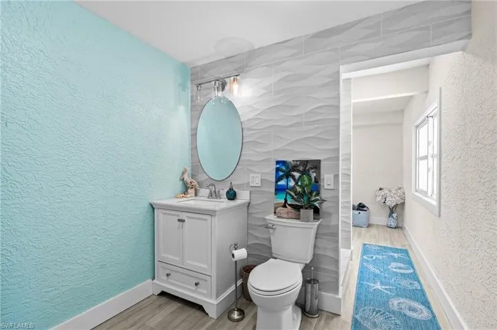 Bathroom featuring a textured wall, vanity, and light wood-style floors