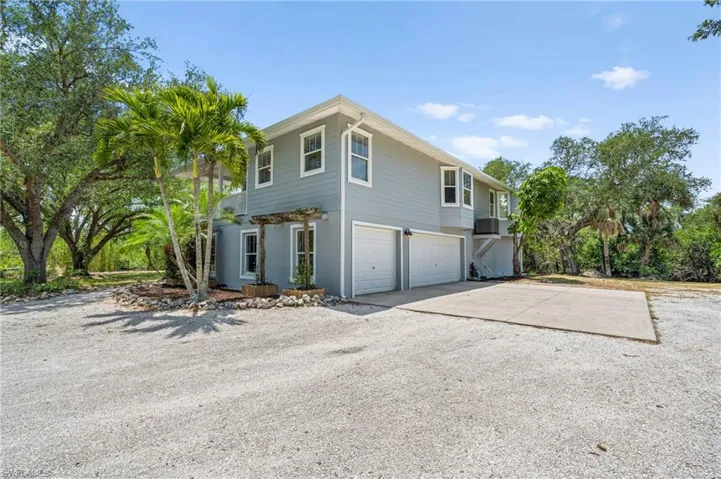 View of property exterior featuring concrete driveway, a garage, and a balcony