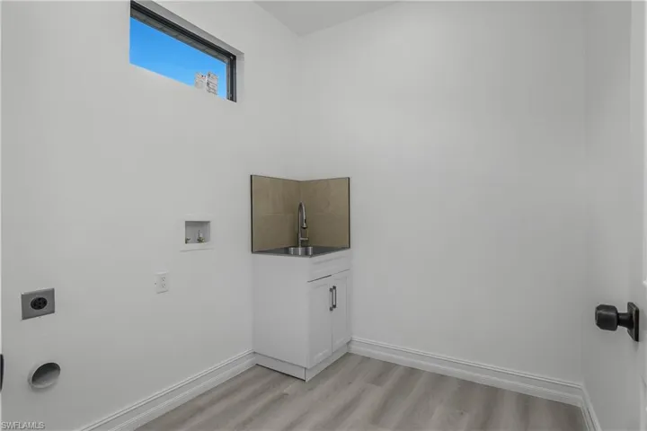 Laundry area with hookup for a washing machine, light wood-type flooring, and hookup for an electric dryer