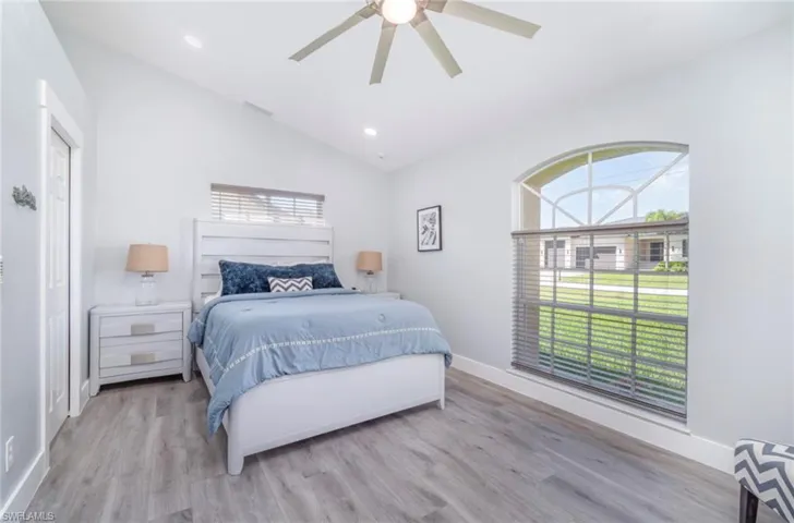 Bedroom with multiple windows, vaulted ceiling, light wood finished floors, recessed lighting, and ceiling fan