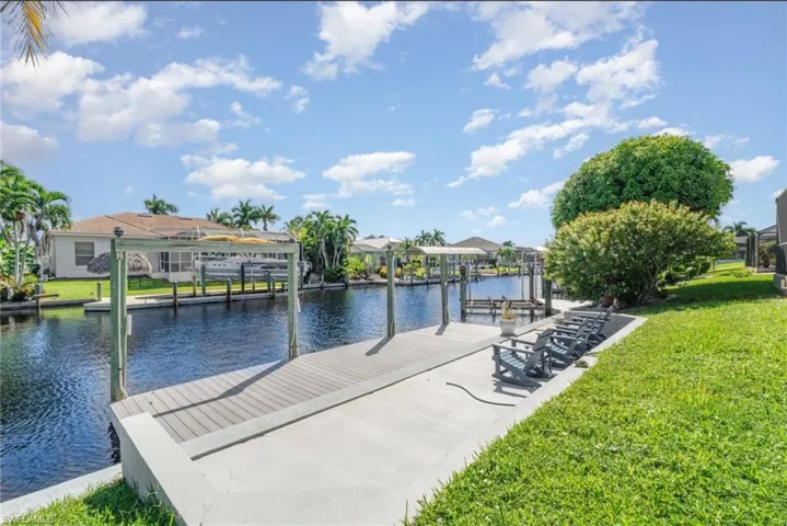Dock with a water view, a lawn, boat lift, and a residential view