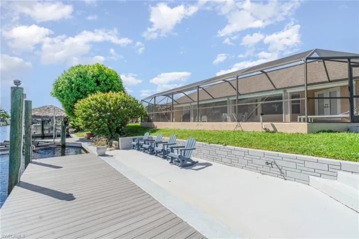 Dock with glass enclosure, a patio area, a sunroom, and boat lift