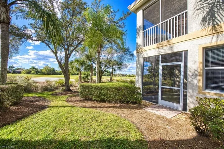View of green lawn with a sunroom and a balcony