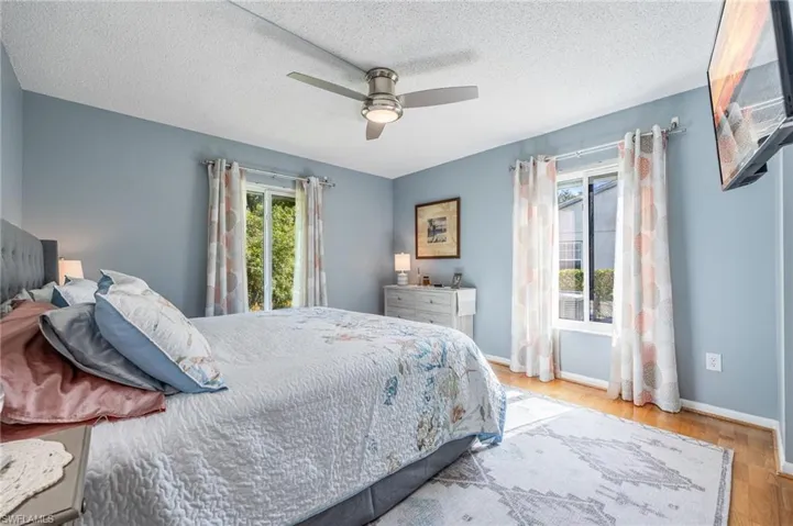 Bedroom with ceiling fan, a textured ceiling, and light wood-type flooring