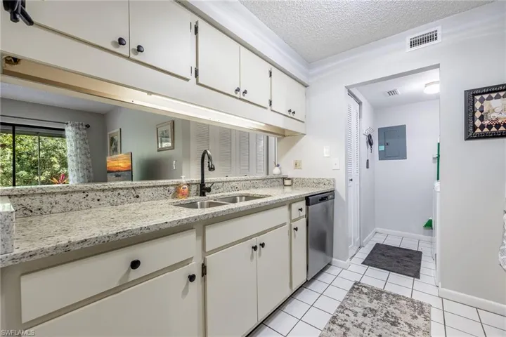 Kitchen featuring white cabinetry, dishwasher, sink, and electric panel