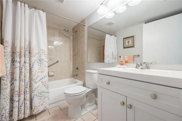 Full bathroom with shower / tub combo with curtain, vanity, toilet, and tile patterned flooring