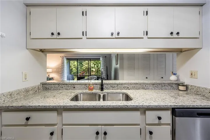 Kitchen featuring light stone countertops, sink, stainless steel dishwasher, and white cabinets
