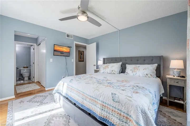 Bedroom featuring ensuite bathroom, ceiling fan, and light wood-type flooring