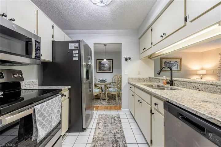 Kitchen featuring appliances with stainless steel finishes, pendant lighting, white cabinetry, sink, and light tile patterned floors
