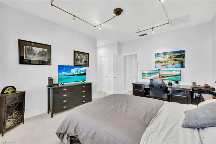 Bedroom with light colored carpet, a closet, and rail lighting