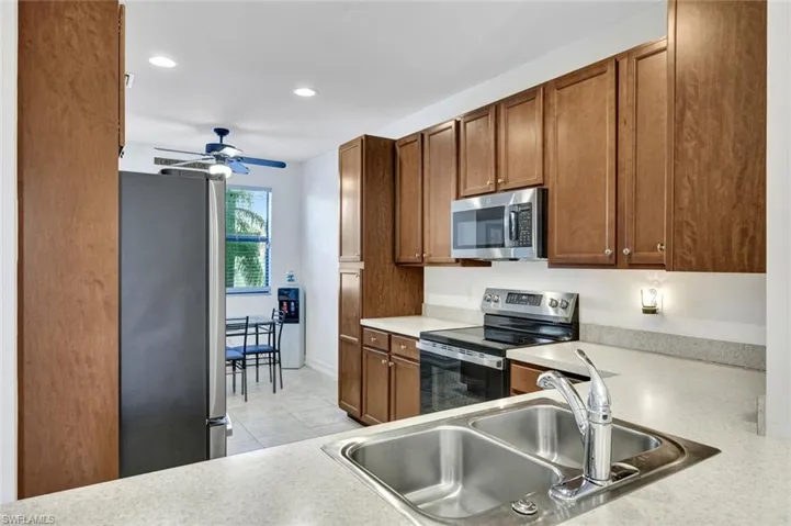 Kitchen with stainless steel appliances, wood finish cabinets, light countertops, recessed lighting, and a ceiling fan