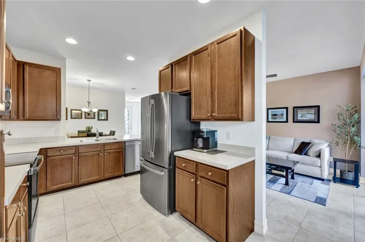 Kitchen featuring wood finish cabinets, light tile patterned floors, light countertops, and stainless steel appliances