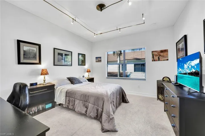 Bedroom featuring light colored carpet and rail lighting