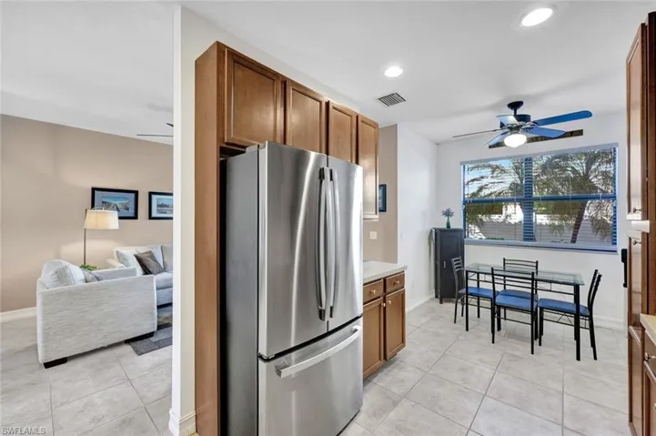 Kitchen with a ceiling fan, freestanding refrigerator, wood finish cabinets, light tile patterned flooring, and recessed lighting