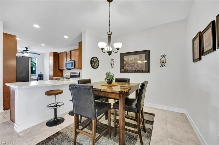 Dining room with suspended lighting, a ceiling fan, and light tile patterned floors