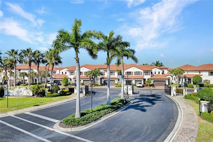 View of asphalt road with curbs, a gated entry, and sidewalks