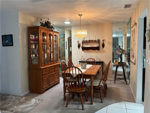 Dining area featuring a central chandelier, wall-mounted shelving with sconces, and full-height mirrored wall panels