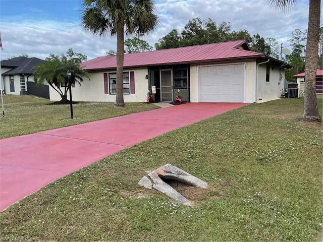 Single story home featuring a garage, stucco siding, driveway, and a metal roof