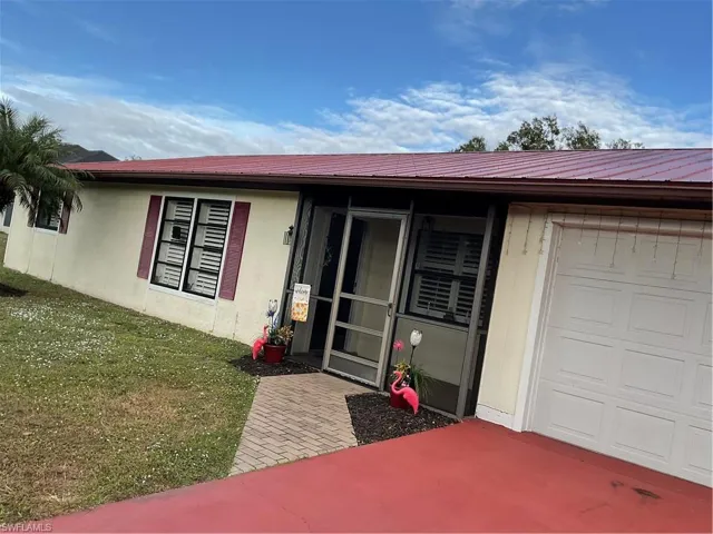 View of front of home featuring stucco siding, a front yard, and a garage