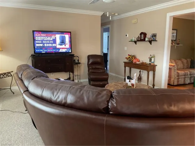 Living room with ornamental molding, a ceiling fan, and carpet floors