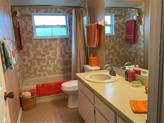 Full bath with shower / tub combo, light tile patterned flooring, healthy amount of natural light, and vanity