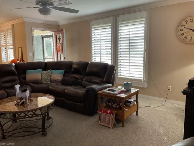 Living room with crown molding, carpet, and a ceiling fan