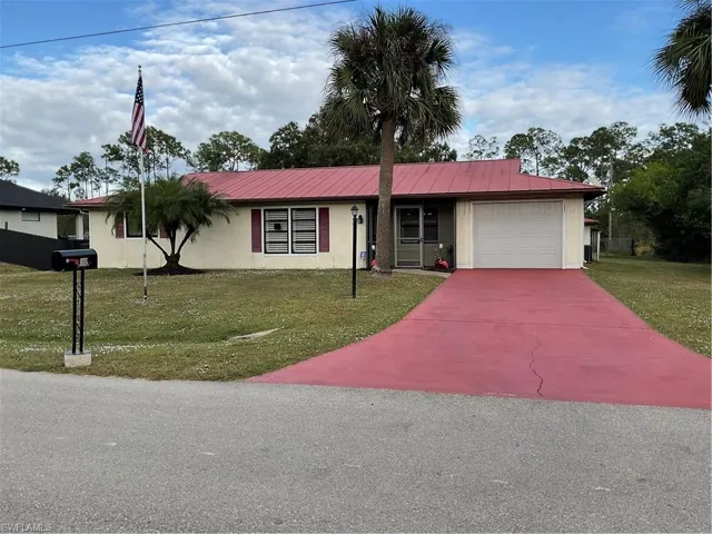Ranch-style home featuring a front lawn, a garage, and a metal roof