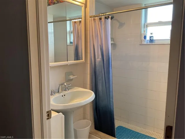 Full bathroom featuring a shower stall and tile walls
