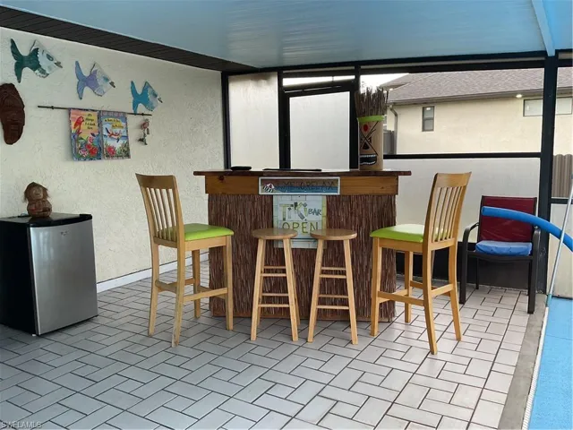 Indoor dry bar featuring a textured wall, fridge, and brick patterned flooring