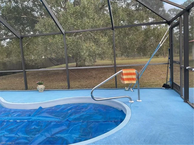 View of swimming pool with a sunroom and glass enclosure