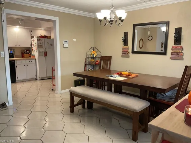 Dining space featuring ornamental molding, a chandelier, and light tile patterned floors
