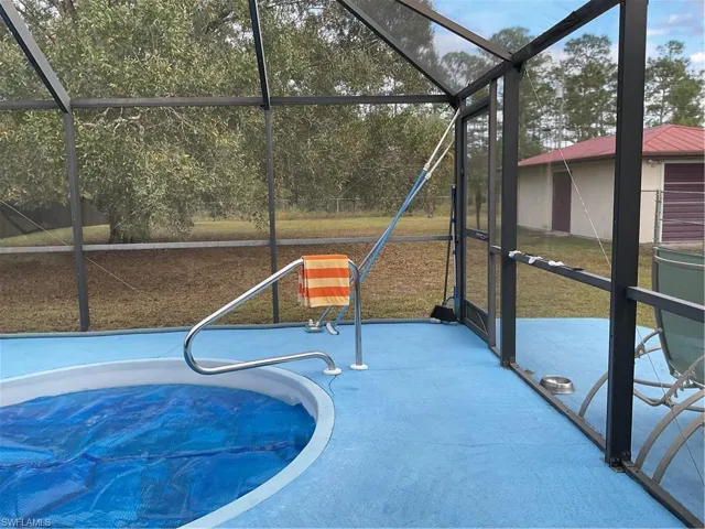 View of pool featuring a sunroom and glass enclosure