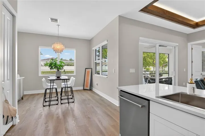 Kitchen featuring stainless steel dishwasher, light wood-style flooring, white cabinets, and plenty of natural light