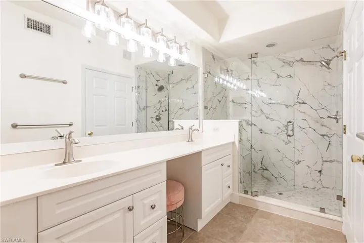 Bathroom featuring tile patterned floors, a shower with door, and vanity