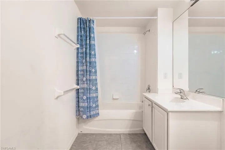 Bathroom featuring vanity, shower / bath combo with shower curtain, and tile patterned flooring