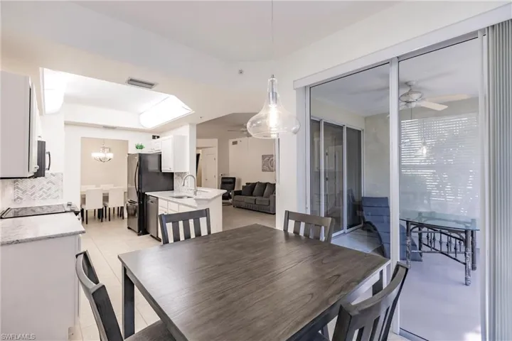 Dining room featuring light tile patterned floors, ceiling fan with notable chandelier, and sink