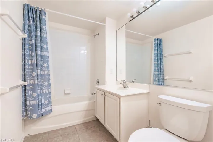 Full bathroom with tile patterned flooring, shower / bath combo, vanity, and toilet