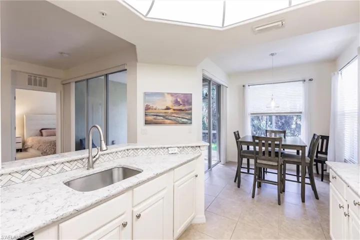 Kitchen featuring plenty of natural light, hanging light fixtures, white cabinets, and sink