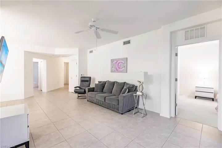 Living room with ceiling fan and light tile patterned flooring