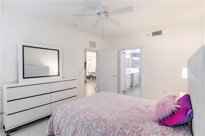 Bedroom featuring ensuite bathroom, ceiling fan, and light tile patterned floors